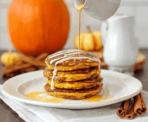 Delicious cinnamon swirl pumpkin pancakes topped with whipped cream and cinnamon, served on a plate for a cozy breakfast.