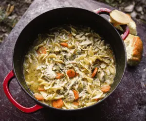 Hearty Dutch Oven Chicken Noodle Soup in a rustic pot with tender chicken, noodles, and vegetables ready to serve